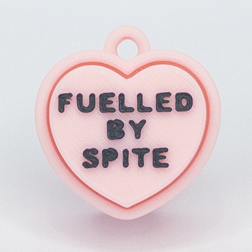 Heart-shaped pink pendant with 'FUELLED BY SPITE' text on a light gray background